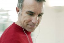 Homem maduro ouvindo música através de fones de ouvido . — Fotografia de Stock