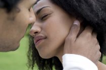 Young couple leaning to kiss outdoors. — Stock Photo