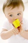 Portrait of baby boy chewing toy block. — Stock Photo