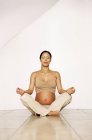 Mujer embarazada en pose de yoga sentado . - foto de stock