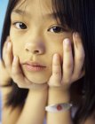 Elementary age Asian girl with medical tag looking in camera, portrait. — Stock Photo