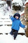 Età elementare ragazzo in abbigliamento invernale giocare sulla strada con la neve . — Foto stock