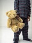 Garçon d'âge préscolaire en pyjama tenant un ours en peluche . — Photo de stock