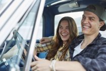 Young couple sitting in car and laughing. — Stock Photo