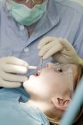 Dentista realizando tratamento odontológico na menina . — Fotografia de Stock