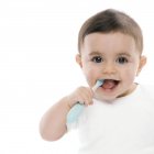 Baby boy using toothbrush on white background. — Stock Photo