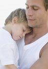 Father cuddling sleeping on chest son. — Stock Photo