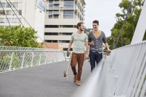 Two young men walking with skateboards on street. — Stock Photo