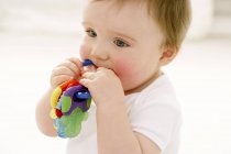 Retrato del bebé masticando el anillo de dentición . - foto de stock