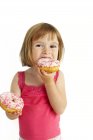 Menina pré-escolar comer donuts no fundo branco . — Fotografia de Stock