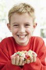 Fröhlicher Junge mit Süßigkeiten in der Hand. — Stockfoto