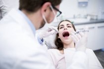 Dentista que dá anestesia ao paciente durante a cirurgia dentária . — Fotografia de Stock