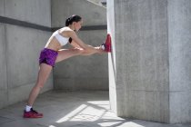 Woman stretching against concrete wall — Stock Photo