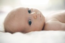 Portrait of infant baby boy lying down on bed. — Stock Photo