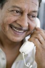 Porträt eines lächelnden reifen Mannes, der am Schnurtelefon spricht. — Stockfoto