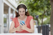 Frau trägt Kopfhörer und hört Musik auf Smartphone. — Stockfoto