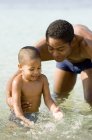 Pai e filho brincando na água do mar . — Fotografia de Stock
