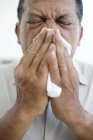 Mature man sneezing into handkerchief. — Stock Photo