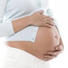 Donna incinta che tiene l'addome, vista ritagliata . — Foto stock