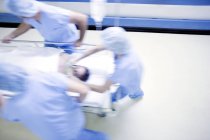 Équipe d'urgence poussant le brancard de l'hôpital avec le patient dans le couloir
. — Photo de stock