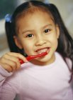 Muchacha joven cepillarse los dientes para prevenir la caries dental - foto de stock