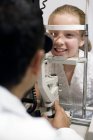 Optician usando lâmpada de fenda para exame ocular menina pré-adolescente . — Fotografia de Stock