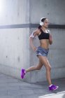 Jeune femme portant des écouteurs courir — Photo de stock