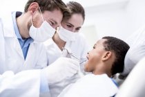 Ärzte untersuchen Jungenzähne in Zahnklinik mit Mundspiegel. — Stockfoto
