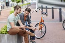 Young men sitting on street wall with smartphone. — Stock Photo