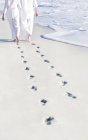 Coppia che cammina sulla sabbia della spiaggia con impronte . — Foto stock