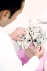 Optician usando phoropter para exame oftalmológico da mulher . — Fotografia de Stock