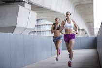 Mujeres jóvenes corriendo al aire libre - foto de stock