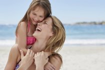 Mother carrying daughter piggy back and laughing. — Stock Photo