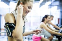 Young woman listening to music while working out in gym. — Stock Photo