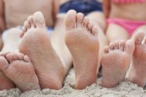 Family sitting on beach with barefoot feet. — Stock Photo