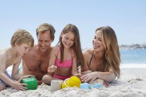 Familie mit zwei Kindern am Strand liegend. — Stockfoto