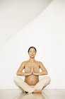 Pregnant woman in seated yoga pose. — Stock Photo