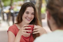 Mujer sosteniendo una taza de café y hablando con un amigo . - foto de stock