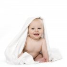 Baby boy sitting under blanket and looking in camera. — Stock Photo