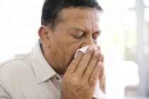 Mature man sneezing into handkerchief. — Stock Photo