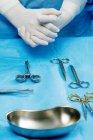 Instrumentos quirúrgicos y manos de médico en quirófano . - foto de stock