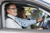 Senior couple traveling by car and woman reading map. — Stock Photo
