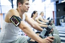 Young man listening to music while working out in gym. — Stock Photo