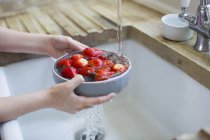 Vue recadrée de la jeune fille lavant des fraises fraîches dans l'évier . — Photo de stock
