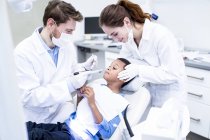 Наляканий хлопчик дивиться на стоматологічне свердло в руці стоматолога . — стокове фото
