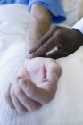 Врач использует пальцы, чтобы чувствовать пульс пациента, крупным планом . — стоковое фото