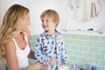 Hijo preescolar cepillándose los dientes con la madre en el baño . - foto de stock