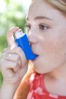 Portrait of teenage redhead girl using inhaler for treating asthma attack. — Stock Photo