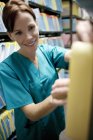 Infirmière fouille les dossiers médicaux dans la salle d'entreposage . — Photo de stock