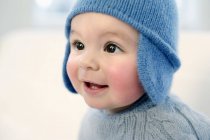 Bébé garçon en bonnet tricoté souriant et détournant les yeux . — Photo de stock
